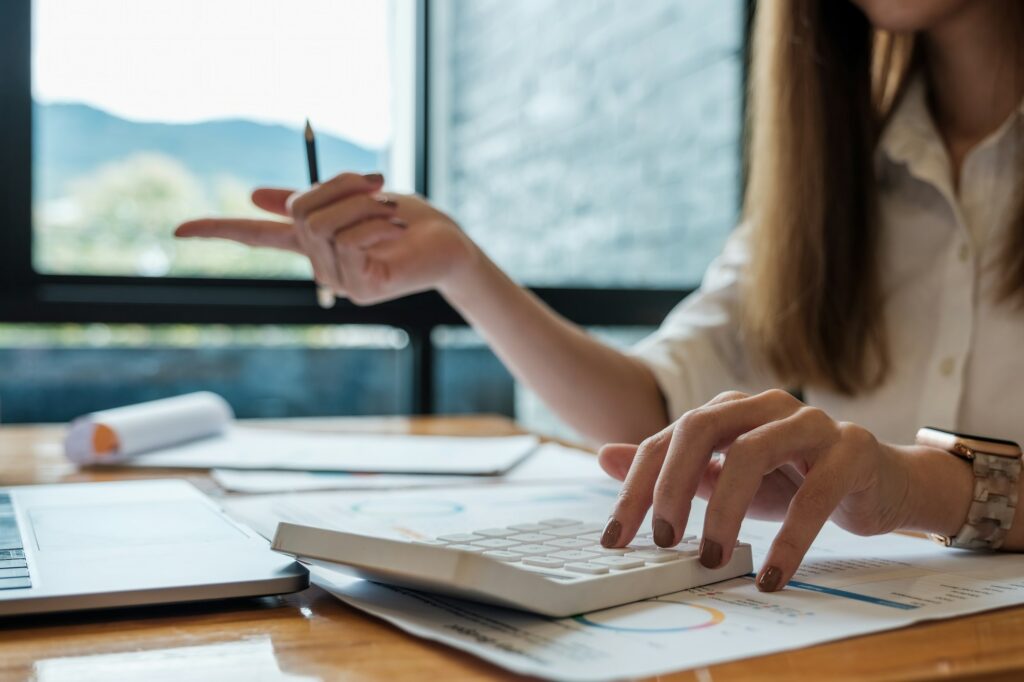 Business woman working in finance and accounting Analyze financial budget with calculator and