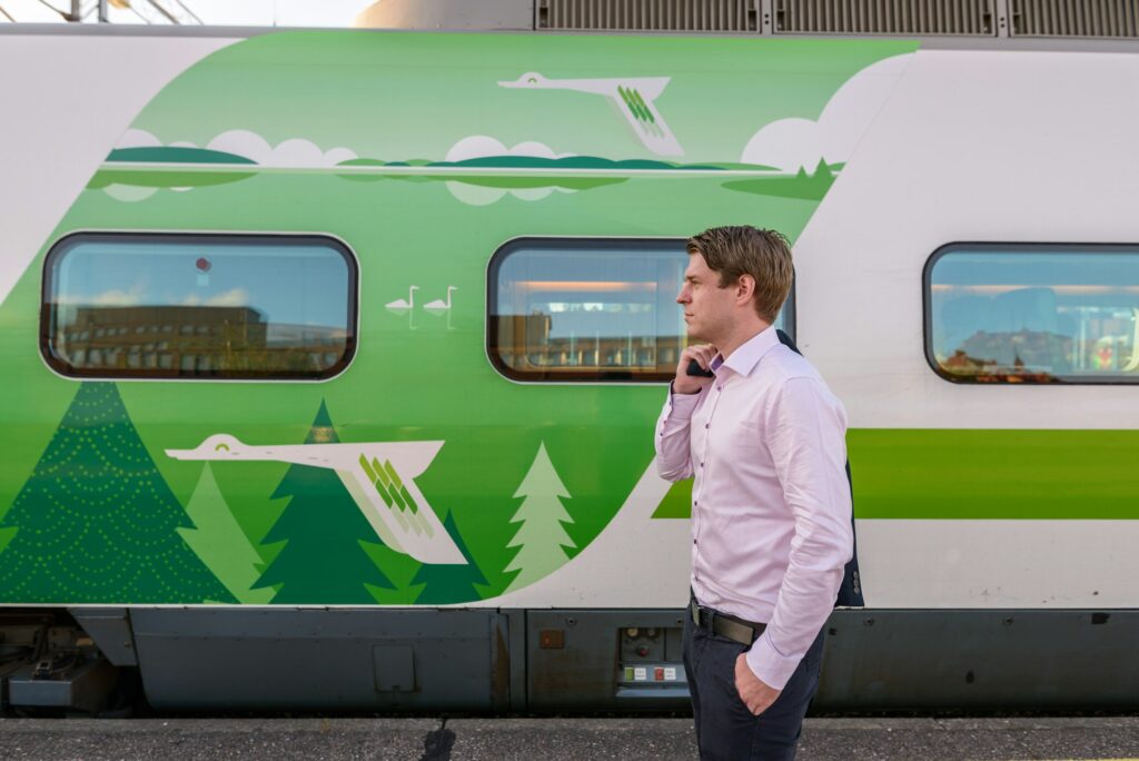 Profile view of young handsome businessman in front of train at railway station